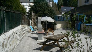 Un patio al aire libre con una parrilla, una mesa y una silla.