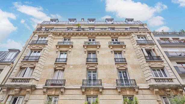 A multi-story building with balconies, large windows, and decorative architectural details. - Charming apartment in the center of Paris (Paris)