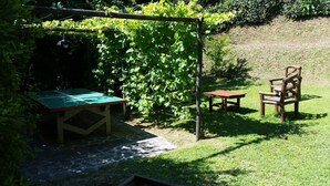Ein Gartenbereich mit Tisch und Stühlen, umgeben von viel Grün.