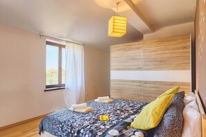 Une chambre à coucher avec un lit, une fenêtre, une tête de lit en bois et un luminaire suspendu.