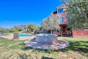 Une maison avec une piscine, un jacuzzi et un espace salon extérieur.