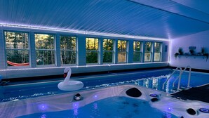 En inomhuspool med en badanka, ett bubbelbad och en stege.