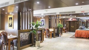 Eine Hotelhalle mit Empfangsschalter, Sitzgelegenheiten und Zierpflanzen.