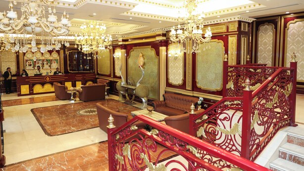 Eine luxuriöse Lobby mit Kristalllüstern, einer imposanten Treppe und komfortablen Sitzbereichen.