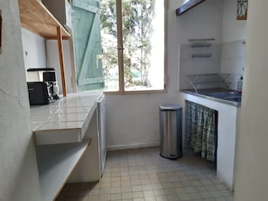 A compact kitchen with a washing machine, a sink, and a trash bin. - Renovated 18th-century farmhouse (Ginasservis)