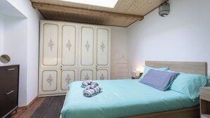 Ein Schlafzimmer mit Dachfenster, einem Bett mit Kissen, einem Schminktisch und einem Kleiderschrank.