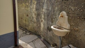 Ein Badezimmer mit einem Steinkonfett, einem Abfluss und einer Betonwand.