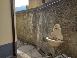 Une salle de bain avec un lavabo en pierre, un drain et un mur en béton.