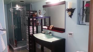 A bathroom with a glass shower enclosure, a dark vanity with a mirror, and a toilet.