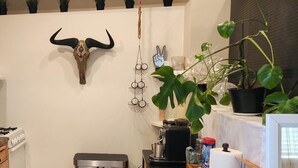 A kitchen with a stainless steel stove, a trash bin, a coffee machine, and a counter with various items.