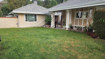 A residential property with a well-maintained lawn, a covered porch, and a two-story house with a tiled roof.