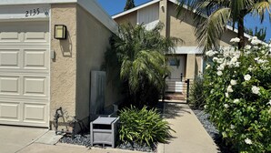 A residential building with a garage, a small outdoor utility shed, and a well-maintained garden with various plants and flowers.