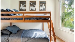 A bunk bed with a lower bed and a window with a view of greenery.