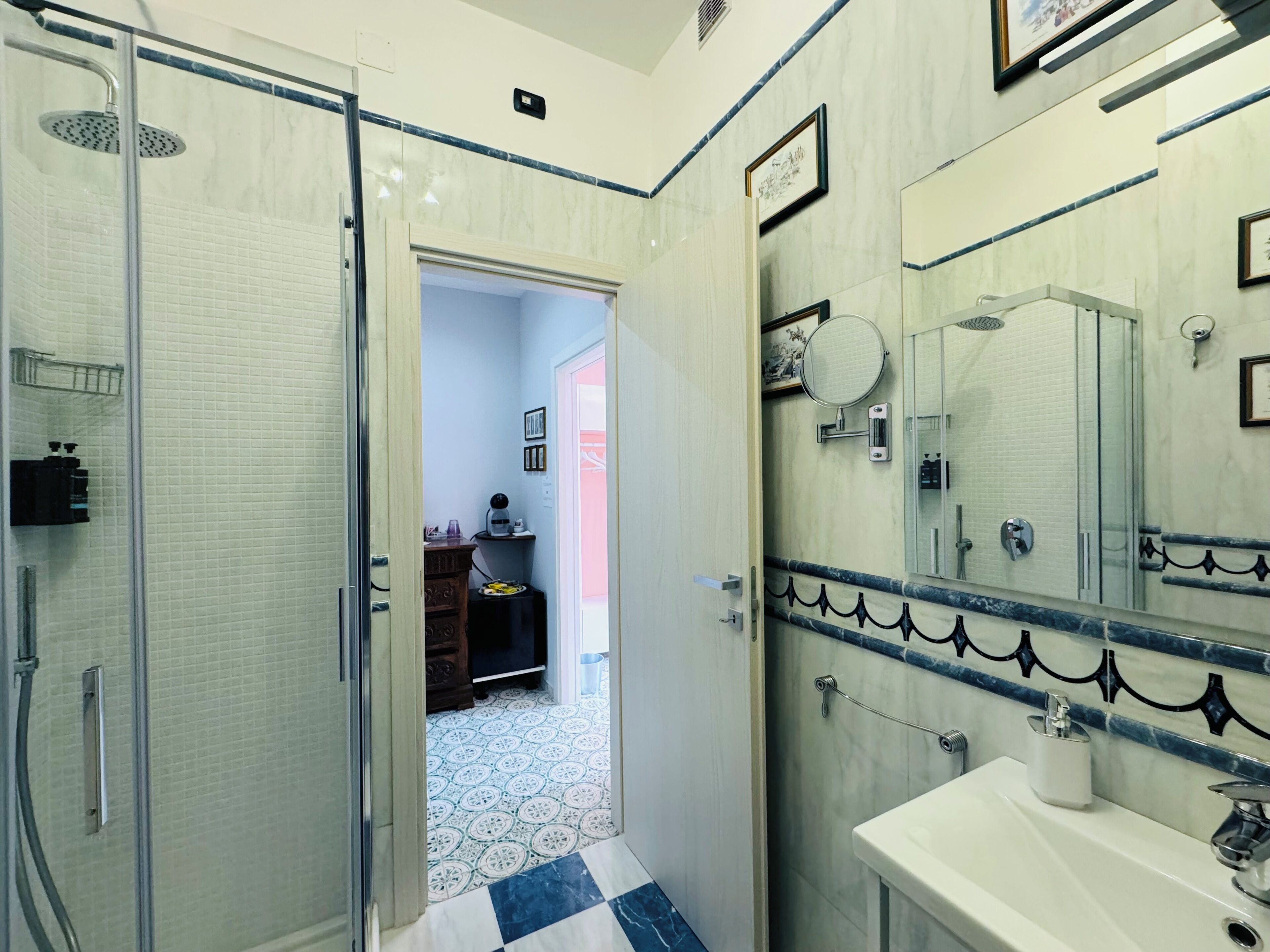 Un baño con ducha, lavabo, espejo y puerta que da a un pasillo.