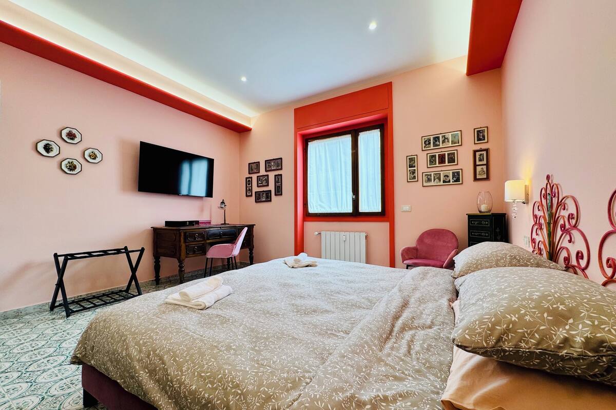 Un dormitorio con cama, escritorio, silla, televisor y ventana.