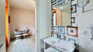 Un baño con lavabo, espejo y perchero para toallas.