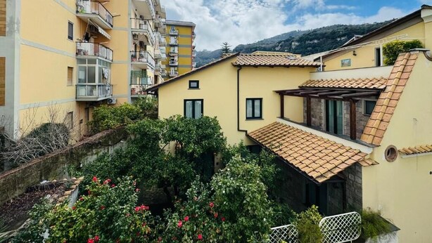 Zona residencial con edificios de varios pisos, un patio con vegetación y cielo despejado.