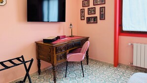 Una habitación con una televisión de pantalla plana montada en la pared, un escritorio con una silla y un radiador.