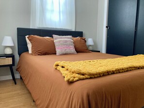A neatly made bed with a brown bedspread and a yellow throw blanket, flanked by two nightstands with lamps and a woven basket. - the Sheep Shack #6204 - Private Hot Tub - Mountain Views - 3 bedrooms - Fire Pit (Estes Park)