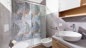Ein modernes Badezimmer mit Dusche, Bidet und einem großen Waschbecken.