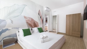 Ein modernes Hotelzimmer mit einem großen Bett, einem Kleiderschrank und einem an der Wand befestigten Fernseher.