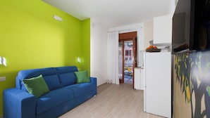 Ein Zimmer mit einem blauen Sofa, einem weißen Kühlschrank und einer grünen Wand.