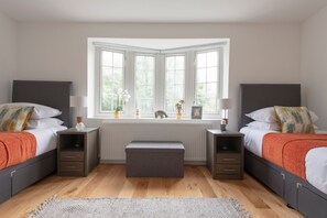 A bedroom with two beds, a window with a view, a radiator, and bedside tables with lamps. - Spacious 4BR Townhouse for 9 near Tufnell Park & Holloway (London)