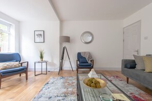 A living room with a sofa, armchair, floor lamp, and a coffee table with a bowl of snacks. - Spacious 4BR Townhouse for 9 near Tufnell Park & Holloway (London)