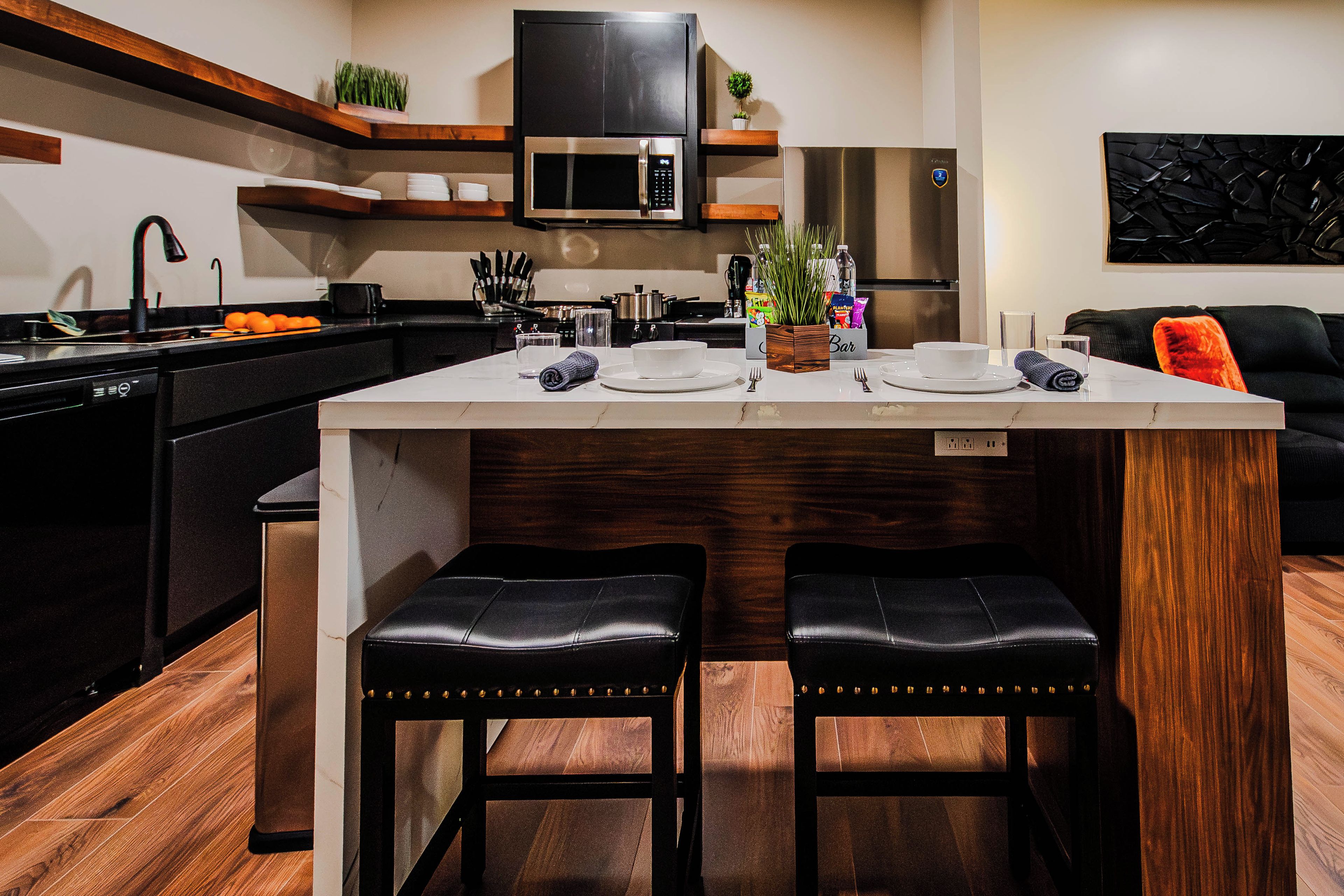 A modern kitchen with a central island, bar seating, and a built-in microwave.