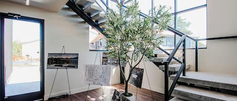 Un escalier au design moderne, une plante en pot et des plans d’architecture exposés sur des chevalets.