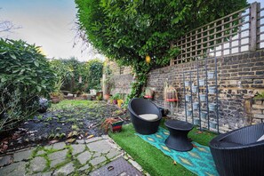 A garden with a brick wall, potted plants, and outdoor furniture. - Cosy 1 bed Flat in Greenwich With Private Garden (London)