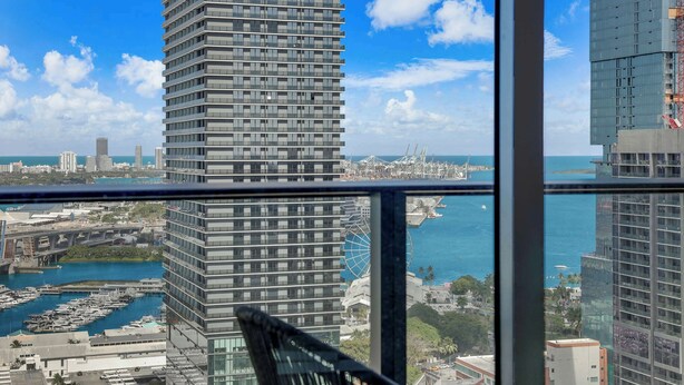 Un edificio alto con vistas a un puerto deportivo y una noria.