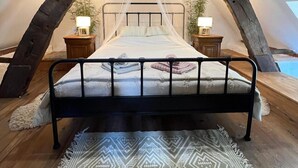 Una camera da letto con un letto, due comodini, un tappeto decorato e una struttura a soffitto in legno.