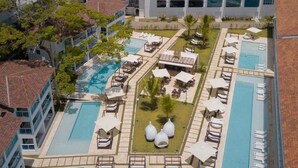 A resort with multiple swimming pools, lounge areas, and a view of the ocean. - Award-Winning Beachfront Resort Penthouse | Pools, Dining & Kite Beach (Cabarete)