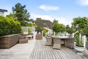 Eine Terrasse mit Korbmöbeln, einem Tisch und einem großen Sonnenschirm.