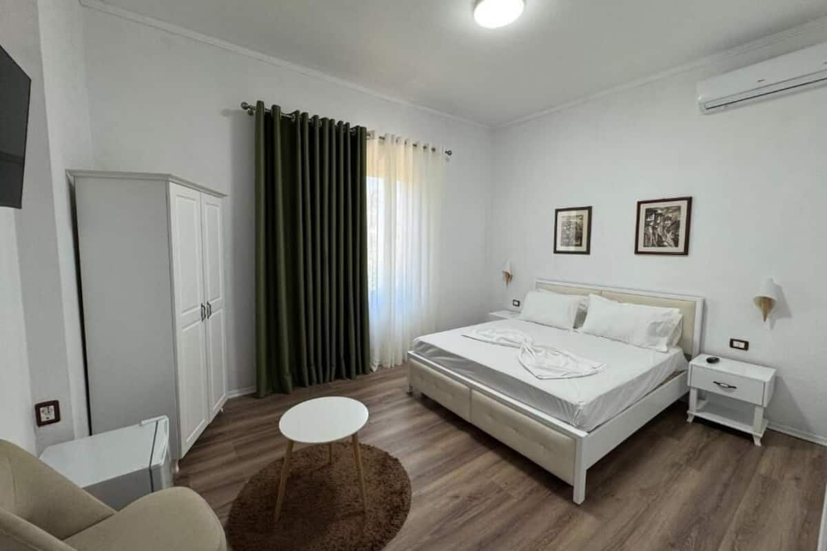 Um quarto com cama, mesa de cabeceira, luminária e uma cadeira.