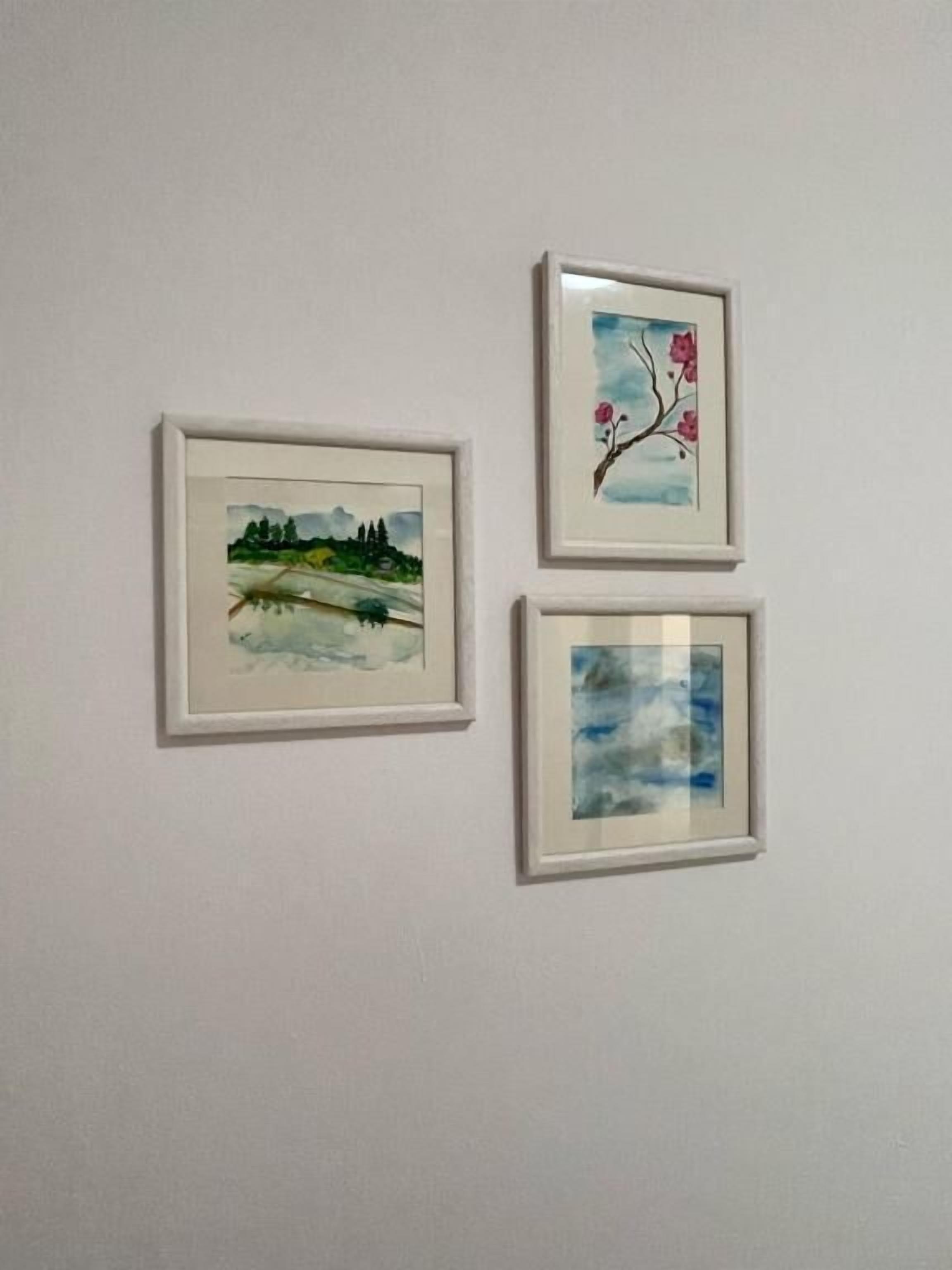 Drie ingelijste kunstwerken aan een effen muur.