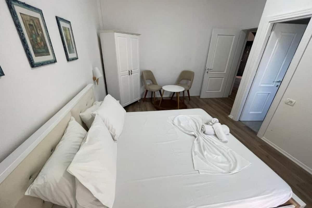 Quarto de hotel com cama, duas cadeiras, guarda-roupa e porta.