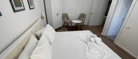 Habitación de hotel con una cama, dos sillas, un armario y una puerta.
