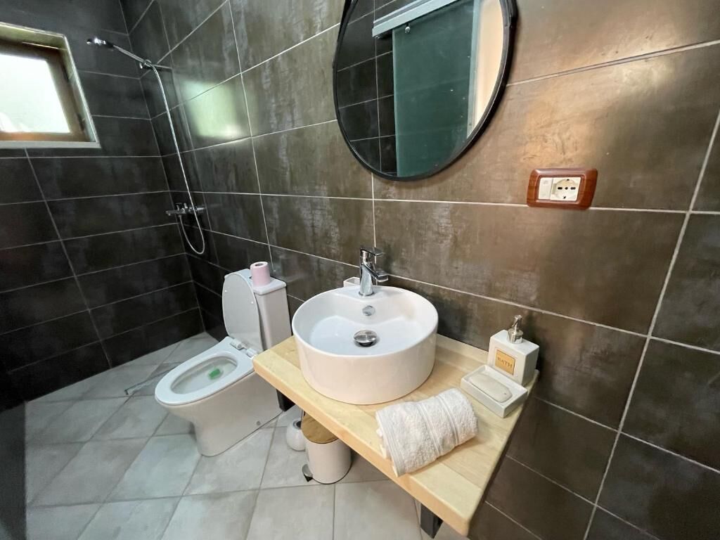 Un baño con inodoro, lavamanos, espejo y ducha.