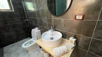 Un baño con inodoro, lavamanos, espejo y ducha.