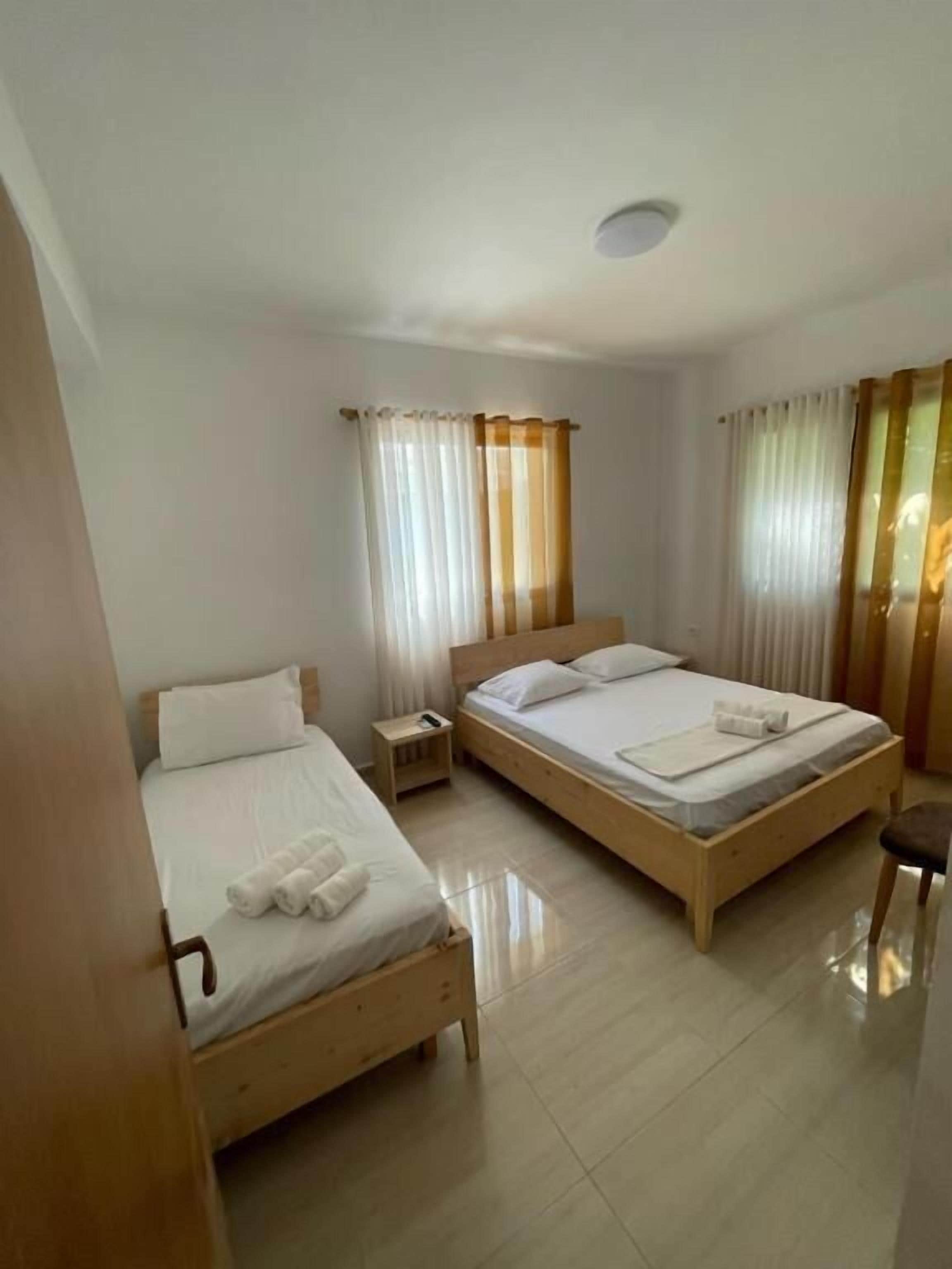 Una habitación de hotel con dos camas de madera, una mesita de noche y una silla.