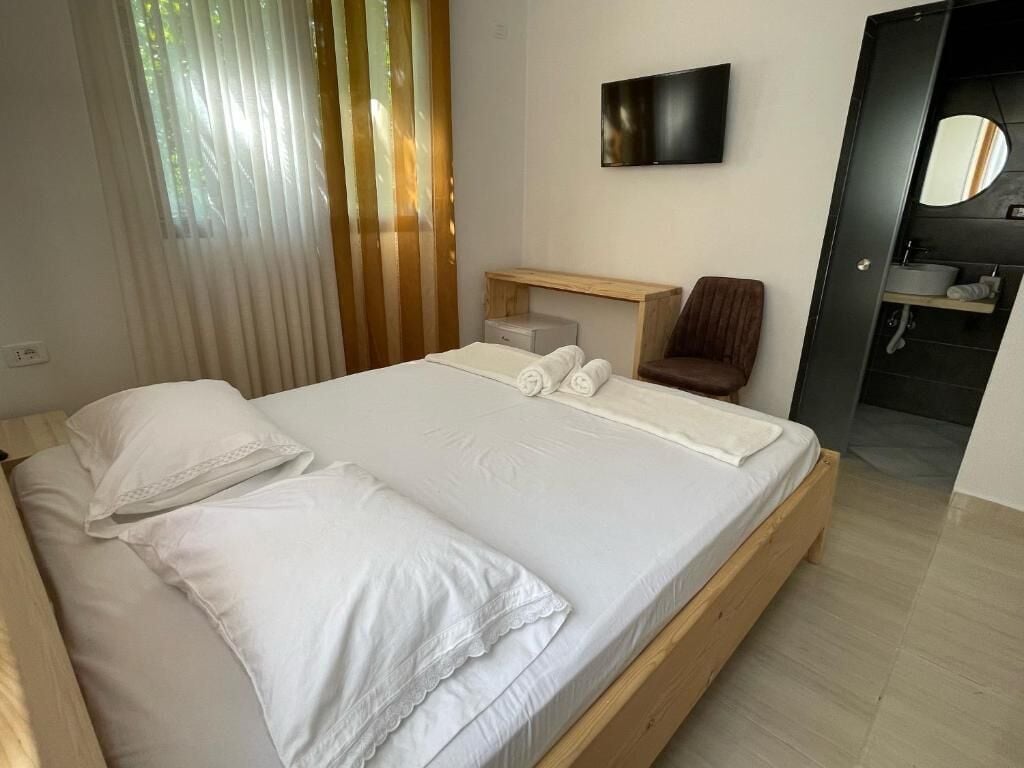 Un dormitorio con cama, televisión, escritorio, silla y baño.