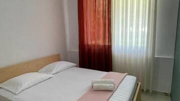 Un lit simple avec une literie blanche, une tête de lit en bois et une couverture rose.