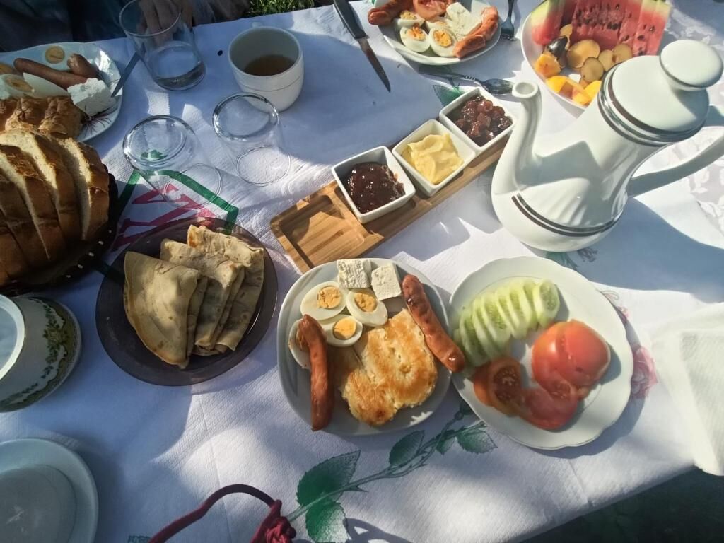 Une table sur laquelle on trouve divers aliments, notamment du pain, des œufs, des saucisses et une pastèque.