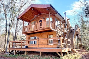 Eine Blockhütte mit Balkon, Treppe und Terrasse.