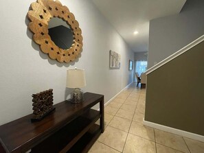 A hallway with a wooden console table, a mirror, and a lamp. - Storey Lake 4BR Retreat, Private Pool, Sleeps 10 (Kissimmee)