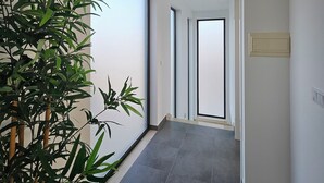 En gang med stor skydedør, en potteplante og en lampe i loftet.
