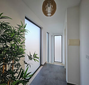 A hallway with a large sliding door, a potted plant, and a ceiling light fixture.