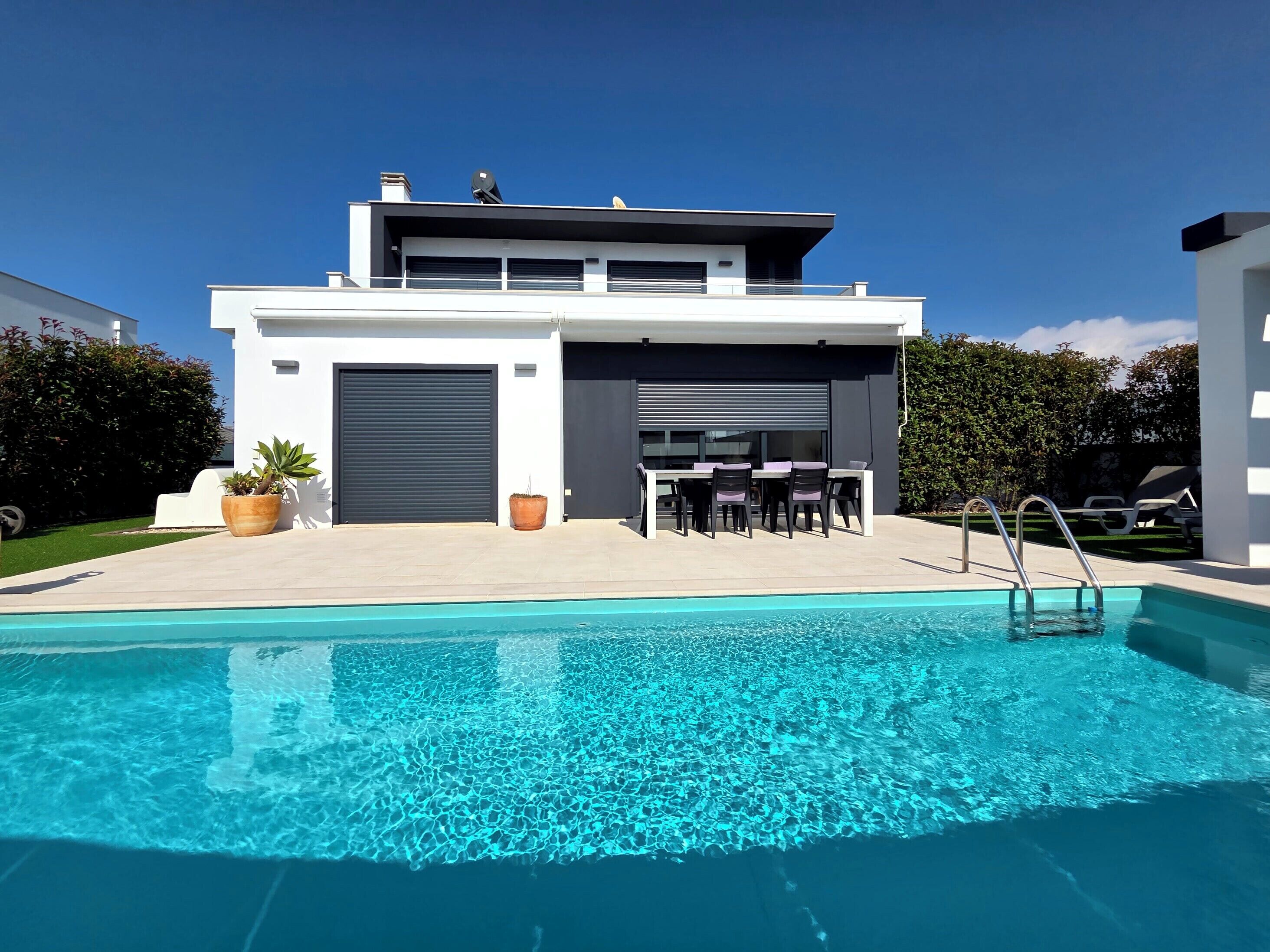 Uma casa moderna de dois andares com piscina em primeiro plano.